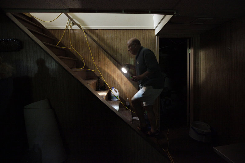 Without power since Tropical Storm Irene hit the state Sunday, Ron Corsi heads up the stairs from the basement of his house in Havertown, Pa.