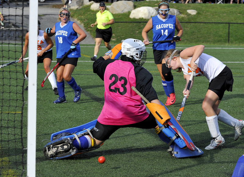 Katie Cawley of North Yarmouth Academy tucks a shot under Sacopee Valley goalie Ashley Pingree during their field hockey opener Thursday. Katherine Millett, left, provided the assist. Defending for Sacopee were Rachel Anderson (18) and Christina Metcalf. NYA won, 4-1.