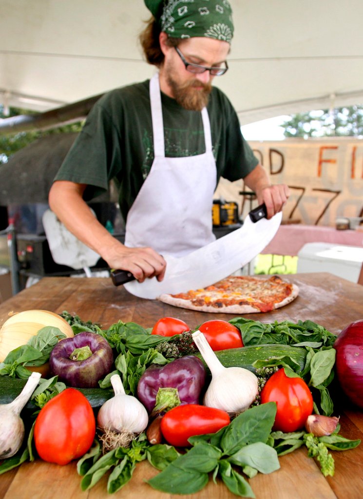 Jeff Knox of Harvest Moon Pizza cuts a pie just baked in the outfit’s mobile wood-fired oven.