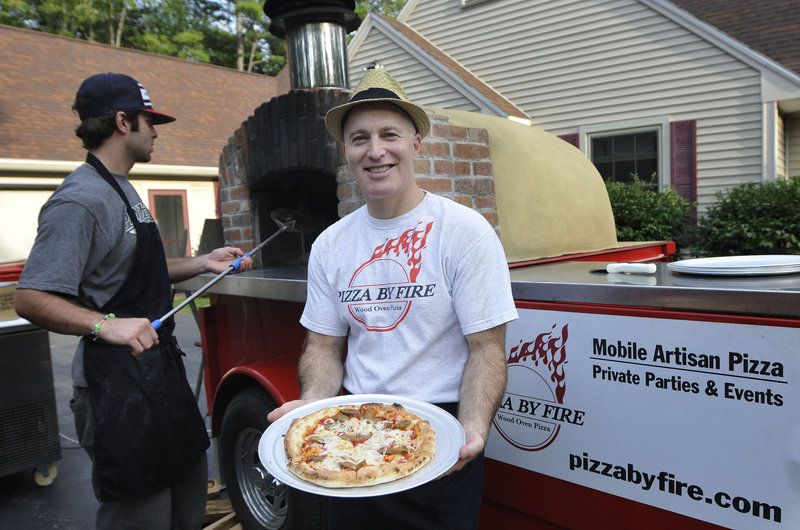 As employee A.J. Ellison keeps watch on the oven, Andrew Steinberg of Pizza by Fire shows off his “Abe Froman” pie featuring hot Italian sausage, mozzarella and crushed tomato. Steinberg was catering at a private party last week.
