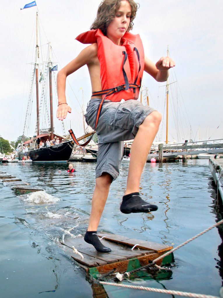 Aidan Acosta, 13, of Rockport leaps for the dock while competing in the lobster crate race on Saturday during the Camden Windjammer Festival.