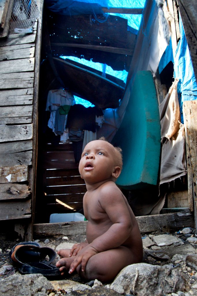 A baby boy sits outside his family’s makeshift home last month in the Champs de Mars tent city near the crumbling National Palace in Port-au-Prince, Haiti.