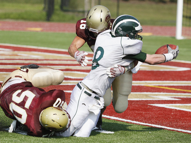 Andrew Libby of Thornton Academy puts a high hit on Matt Burnell of Bonny Eagle, forcing a fumble that ended the Scots' final opportunity. Making the lower-body hit for the Golden Trojans is Chris Madden.