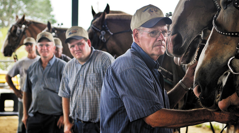 Men wait with their teams of horses Monday while watching a pulling competition on the last day of Windsor Fair.