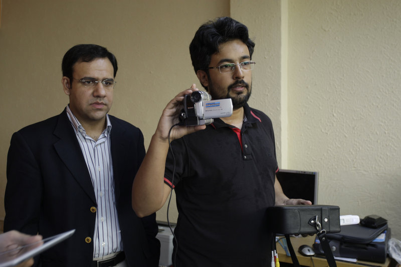 Umar Saif, left, works with his colleague Yaser Awan in Lahore, Pakistan. Only 11 percent of all Pakistanis use the Internet, but many more use cell phones. “The thing to do is bring whatever you have on the Internet on the phone lines, because that is what gets used the most,” Saif said.