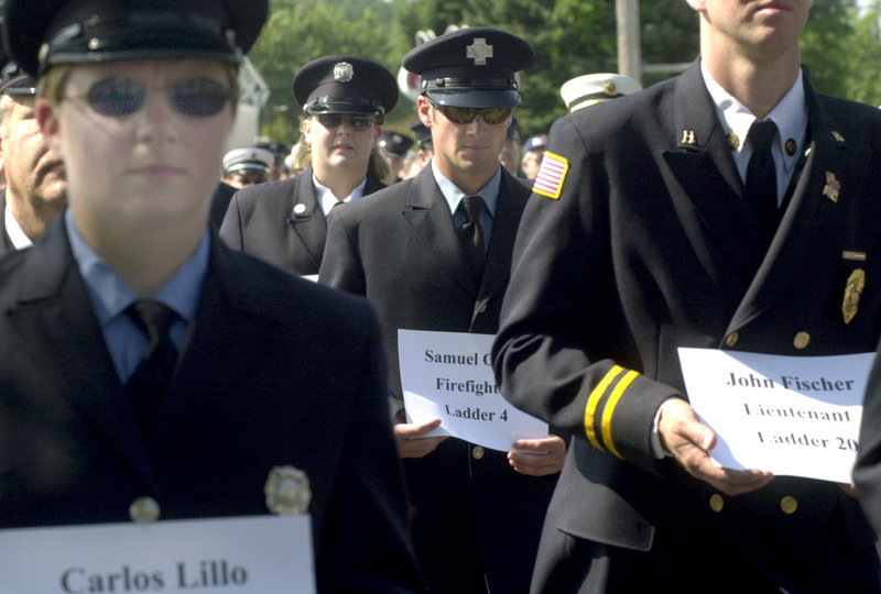 Maine firefighters hold placards with the names of New York firefighters killed on 9/11 as they parade in Freeport to open the Maine State Federation of Firefighters convention in 2002.