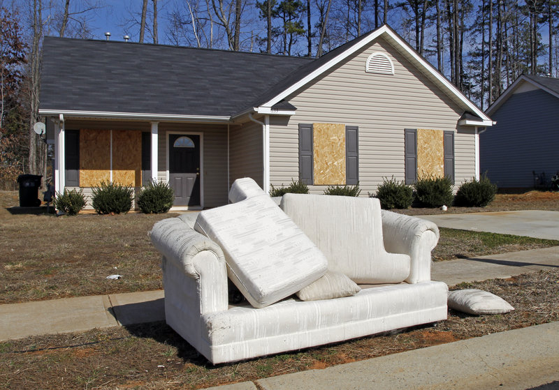 A discarded sofa sits in front of an abandoned house in the Windy Ridge subdivision of Charlotte, N.C., where many sought starter homes in recent years. A Pew Charitable Trusts study has found nearly a third of Americans with a middle-class upbringing have slipped down the economic ladder.