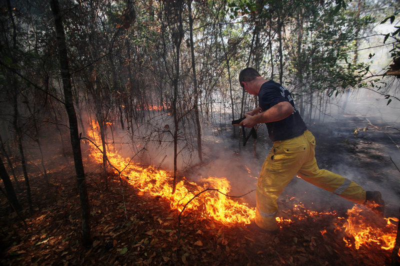 A firefighter jumps across the fire south of Todd Mission, Texas, in Waller County on Wednesday. Firefighters made progress against one of the most destructive wildfires in Texas history. The fire has claimed more than 33,000 acres, 800 homes and two lives.