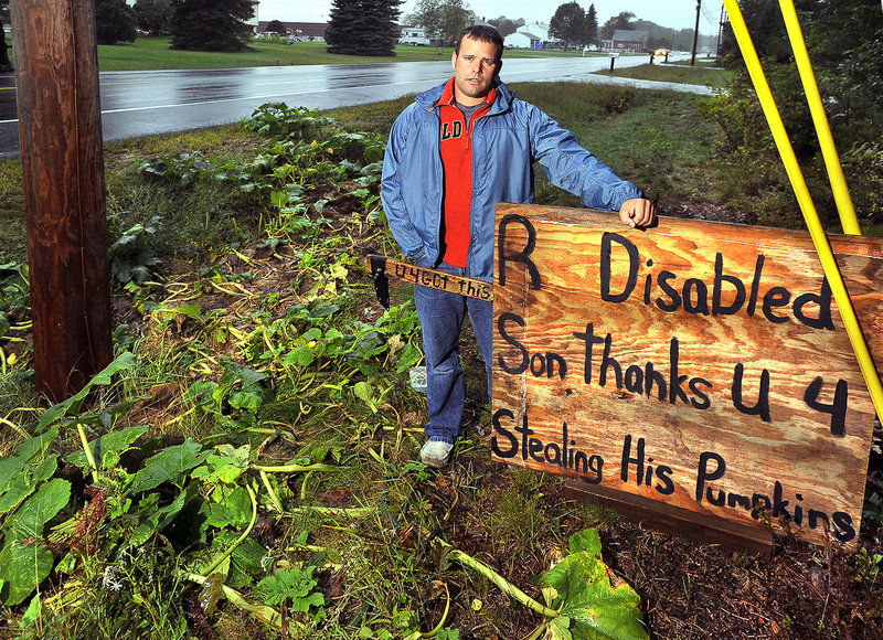 Jason Berry stands in the rain Wednesday with a sign he made to communicate his feelings about someone stealing all the pumpkins from his pumpkin patch on Buxton Road in Saco.