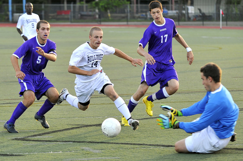 Jamie Gullbrand of Deering goes down to stop a charging Tim Rovnak of Portland as Nathan Finberg, left, and Anthony Verville of Deering move in. Portland won, 2-0.
