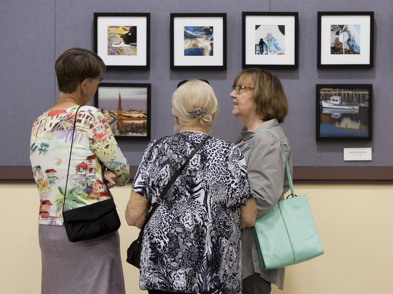 Leslie Anderson, Priscilla Krasnow and Julie Maranan, all of Portland, have a discussion at the Black Frame Art Sale in the Merrill Auditorium rehearsal hall Friday. Last year, the annual event raised about $6,000, organizers said.