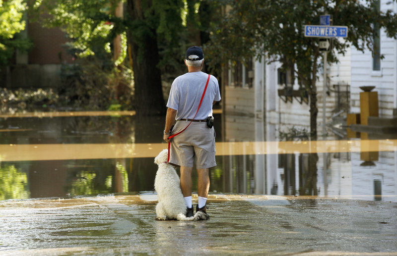 John Wimer and his dog, Carlie, go out Saturday to look at flooding caused by Tropical Storm Lee in Harrisburg, Pa.