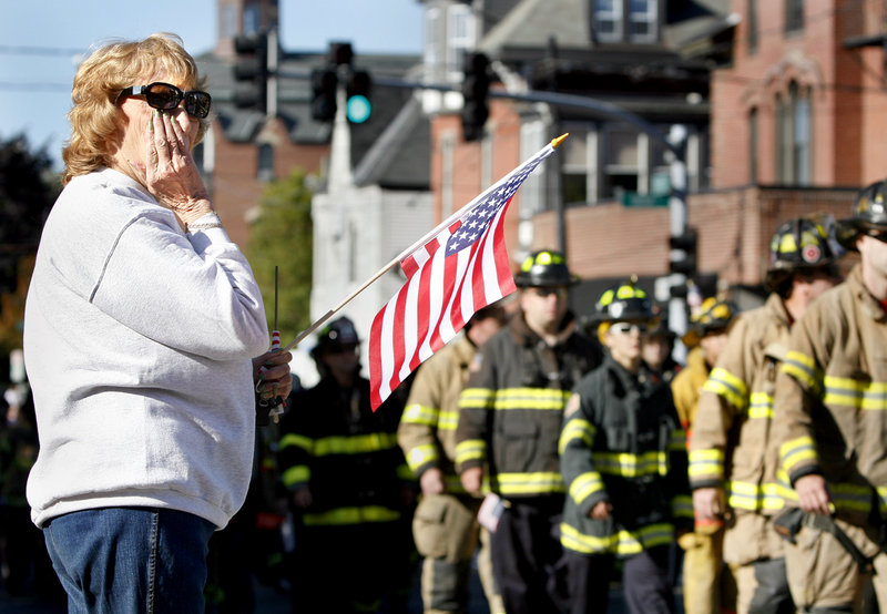 Jeannine Sullivan of Portland wipes away tears as Maine firefighters parade up Congress Street during Portland’s Sept. 11 observance Sunday.
