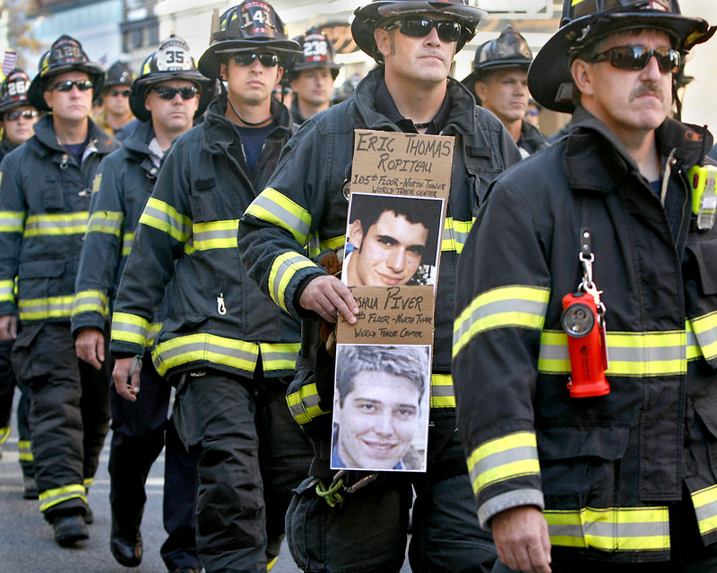 Beau Gleason of the Portland Central Fire Station carries pictures of friends from college, who died on the 105th floor in the north tower of the World Trade Center, during a procession along Congress Street in Portland as part of Sunday’s Sept. 11 observance.