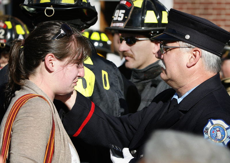 Bob Ewing, a volunteer firefighter with the DeFreestville, N.Y., Fire Department who was part of a rescue and recovery group that went to New York City after the attacks on Sept. 11, 2001, wipes tears from the face of his daughter, Hannah Ewing of Portland, before participating in Portland’s 10th anniversary observance Sunday.