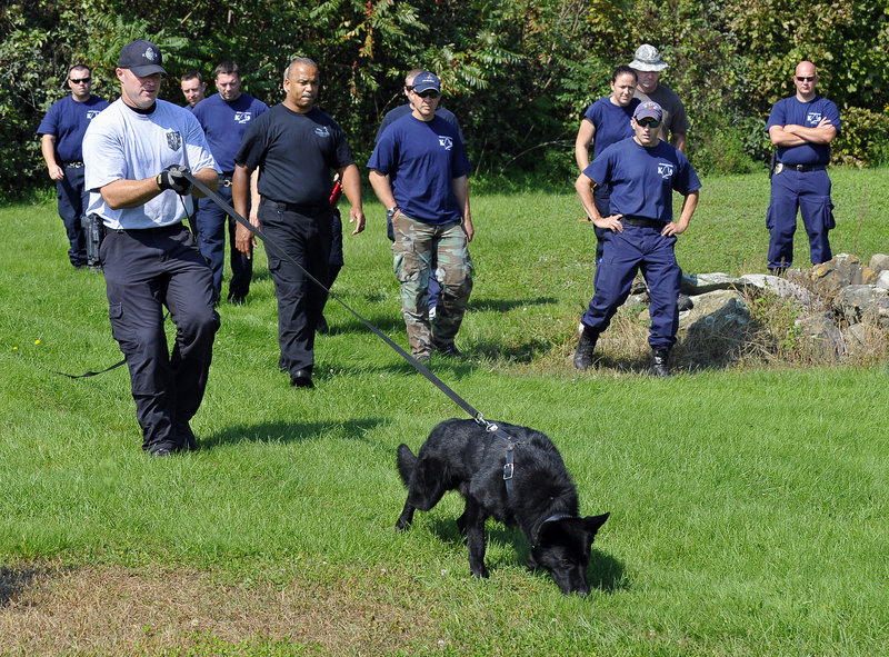 Eric Palmer, a K-9 officer with the Wilmington Police Department in Massachusetts, demonstrates handling technique as Boston lead trainer Troy Caisey, right of Palmer, and Maine canine team members observe Tuesday at a field in Scarborough.