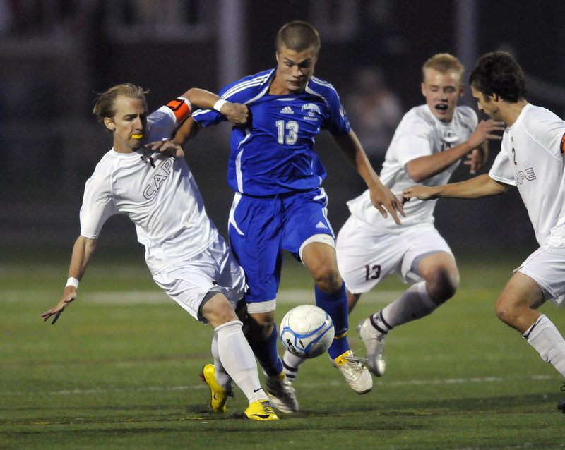 Brandon Tuttle, center, tries to maneuver between Cape Elizabeth's Blake Barritt, left, and Griffin Thoreck during a boys' soccer game Wednesday night at Cape Elizabeth. Falmouth improved to 3-0 with a 2-1 victory.