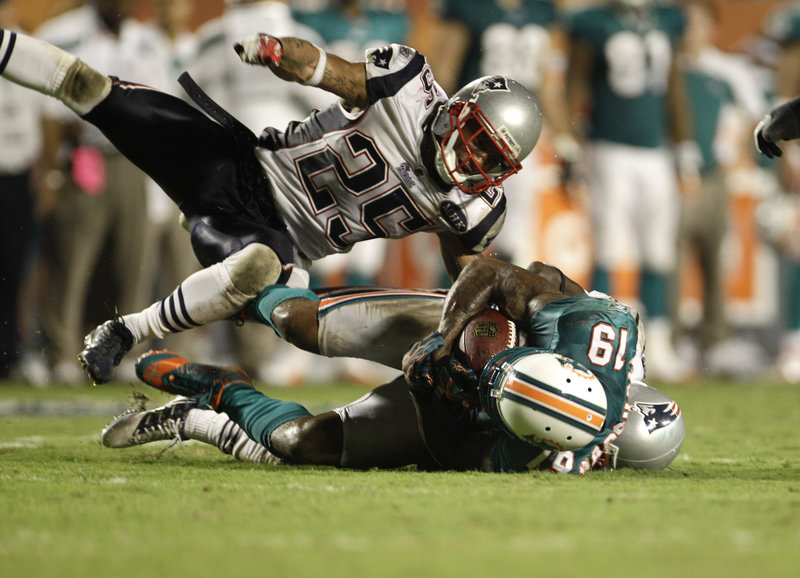 Patrick Chung, top, and Devin McCourty, back, take down Miami’s Brandon Marshall in Monday night’s game. McCourty led the Patriots with 11 tackles, but the Dolphins threw for 416 yards against New England’s secondary.