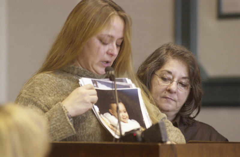 Mary Farrar, right, offers support in 2003 to Susan Goulding as Goulding shows pictures of her daughter at her killer’s sentencing. Farrar retired this week as a victims advocate.