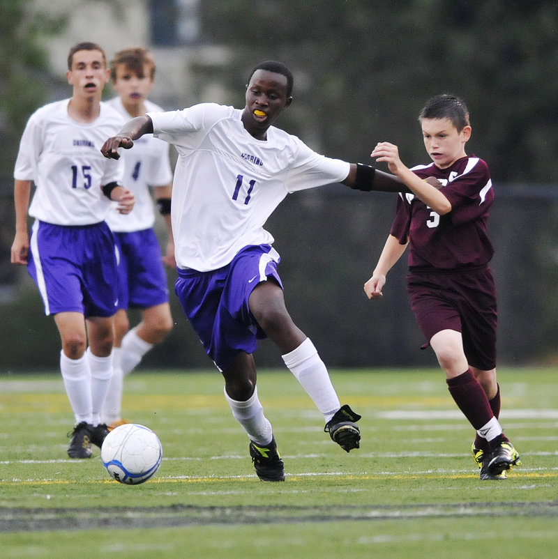 David Ndayshimye of Deering attempts to control the ball and break away while holding off Josh Emard of Noble during their Western Class A schoolboy soccer game Thursday night. Deering won, 2-0.
