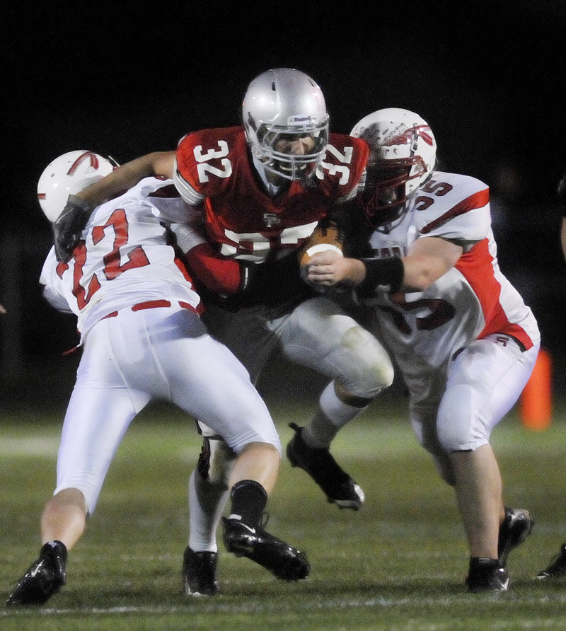 Dan Medici of South Portland looks for room up the middle Friday night between Alex Shain, left, and Andrew Gregoire of Sanford. South Portland stopped a late 2-point conversion attempt by Sanford, then went on to a 42-34 victory at Martin Field. Both teams are 2-1.
