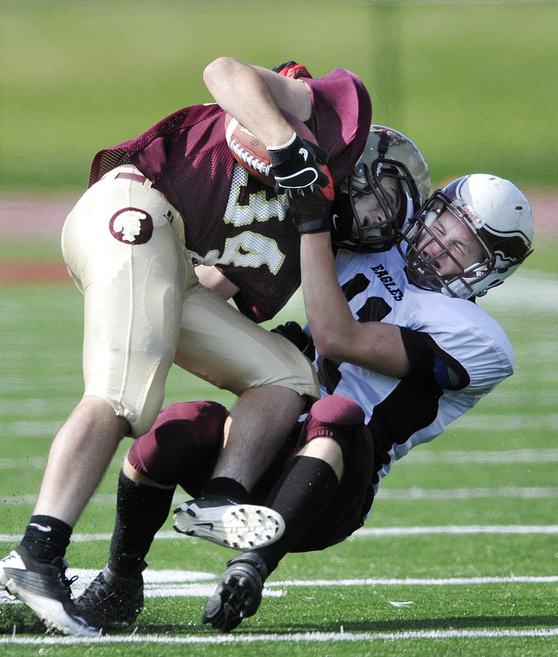 Nick Kenney of Thornton Academy is dragged down by Todd Allen of Windham during their defensive struggle Saturday. Thornton won 7-0 on a first-period touchdown.