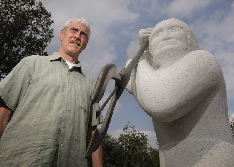 John Banks, natural resources director for the Penobscot Indian Nation, stands next to a sculpture of a native fisherman on Indian Island. "We have always looked at the river as a living, breathing entity in its own right, and we have attempted to approach its recovery in a holistic way," he said.