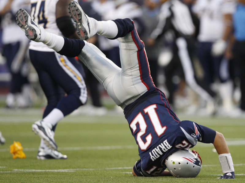 Tom Brady lands on his head Sunday after taking a hit from Chargers lineman Cam Thomas at Gillette Stadium. Brady threw three touchdown passes in the game.