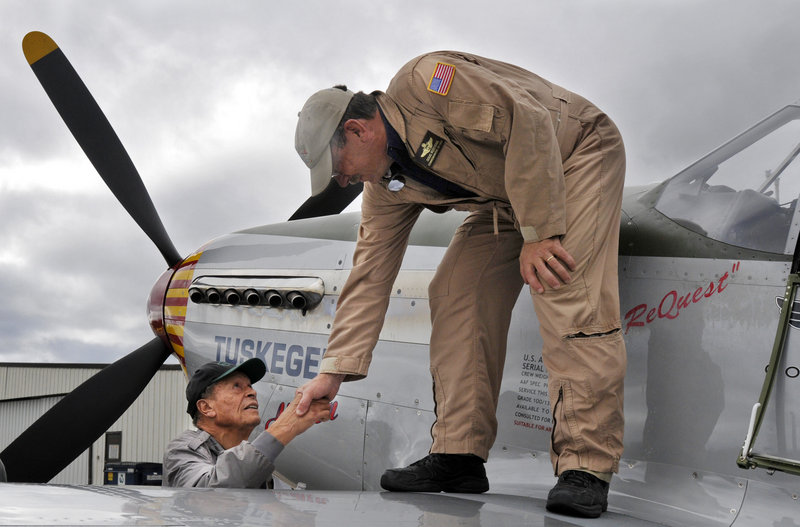 Jim Sheppard shakes hands with Doug Rozendaal of the Commemorative Air Force Red Tail Squadron, which travels the country teaching the history of the Tuskegee Airmen.