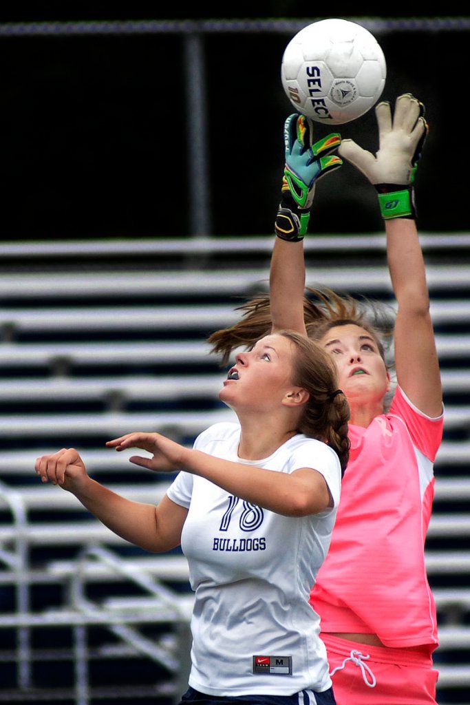 Maris Butler, the goalkeeper for Bonny Eagle, goes high to grab the ball over Ashley Frank of Portland.