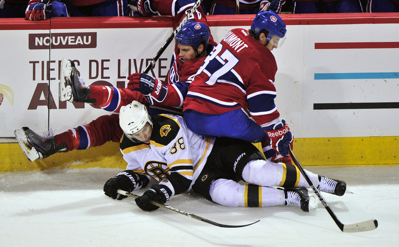 Montreal’s Mike Blunden, rear, and Gabriel Dumont fall over Boston’s Jordan Caron in an NHL exhibition in Montreal.