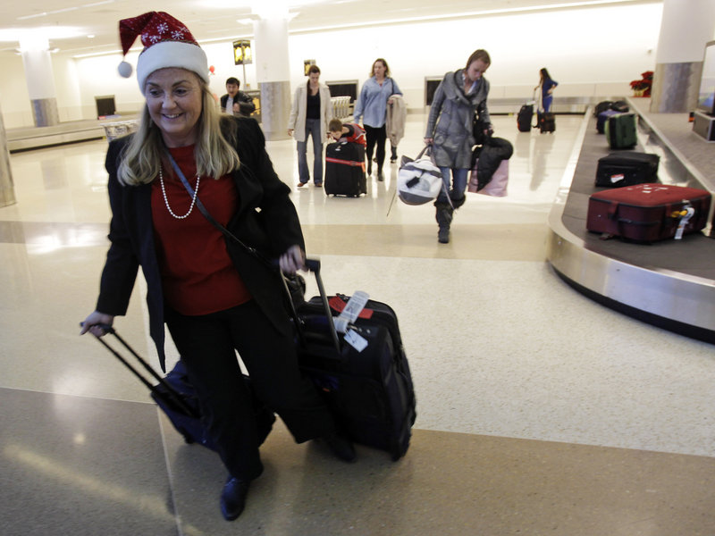 Christmas travelers collect their luggage at San Jose International Airport. Flying on a holiday can cut the cost of airfare.