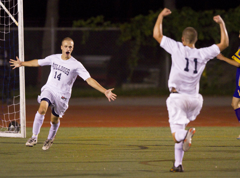 Tim Rovnak, left, celebrates with teammate Paley Burlin after scoring the overtime goal that gave Portland a 3-2 victory against Cheverus on Tuesday night at Fitzpatrick Stadium. Rovnak scored all of the goals for the Bulldogs, who improved to 6-1-1.