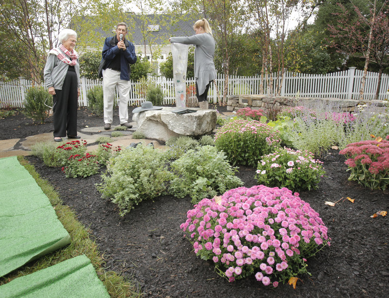 Barbara Bush looks at a bench holding bronze versions of her floppy hat, her favorite book, "Pride and Prejudice," and her favorite sneakers, Keds, Thursday during the dedication of a town garden named after her in Kennebunkport. At center is family friend Ken Raynor, and at right is granddaughter Marshall Bush.