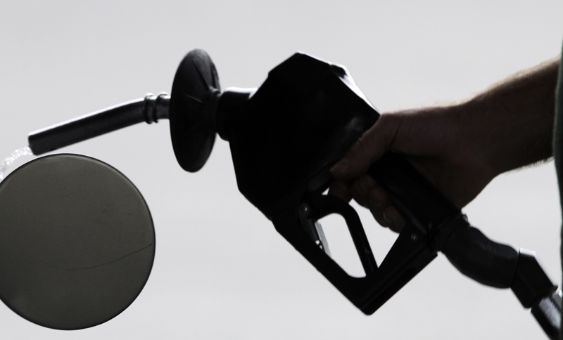 A motorist pulls the nozzle out of his gas tank after fueling his car at a station in Augusta recently. Retail gasoline prices are rising in the U.S. even though motorists are buying less.