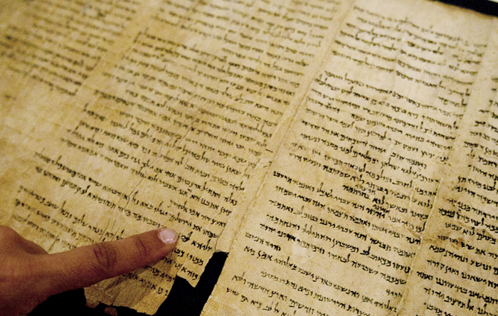 An Israel Museum worker points at the word "Jerusalem" written in the Isaiah Scroll, one of the Dead Sea Scrolls, inside the vault of the Shrine of the Book building in Jerusalem today.