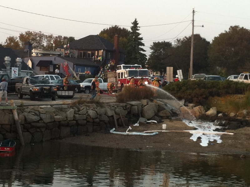 Firefighters spray foam onto the beach and the water near Cape Porpoise pier in Kennebunkport after a pickup truck was pulled from the water Saturday evening.