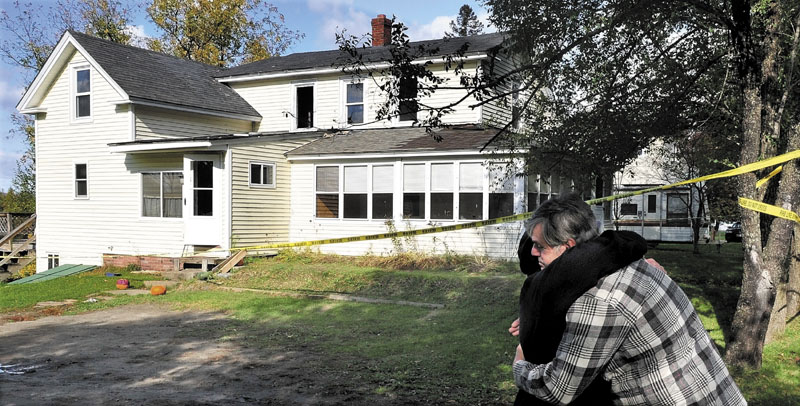 COMFORT: Homeowner Mellaney Drew is consoled by neighbor Mike Parlin outside Drew's home in Hartland on Monday as an investigator with the state Fire Marshal's Office and Hartland Fire Chief Don Neal try to determine the cause of the fire that seriously damaged the home Saturday night.