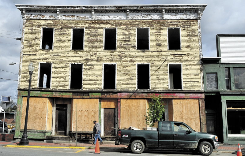 EYESORE: Alan Griffeth walks past the Sweet Memories of Maine building at the corner of Madison Ave. and Commercial Street in Skowhegan where he and demolition crews are removing windows, wiring and plumbing before the building and two others will be torn down this fall.