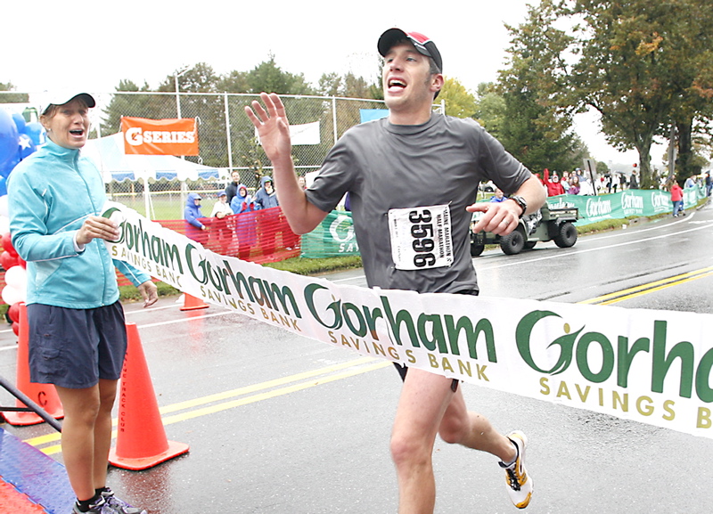 Maine Marathon winner Evan Graves waves to supporters as he crosses the finish line during the 20th running of the Maine Marathon today in Portland.