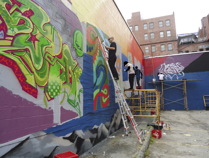 Matt W. Moore, front, and other artists work on the mural at the Asylum nightclub. They also painted three other walls of the building, one of which includes a whimsical puffin.
