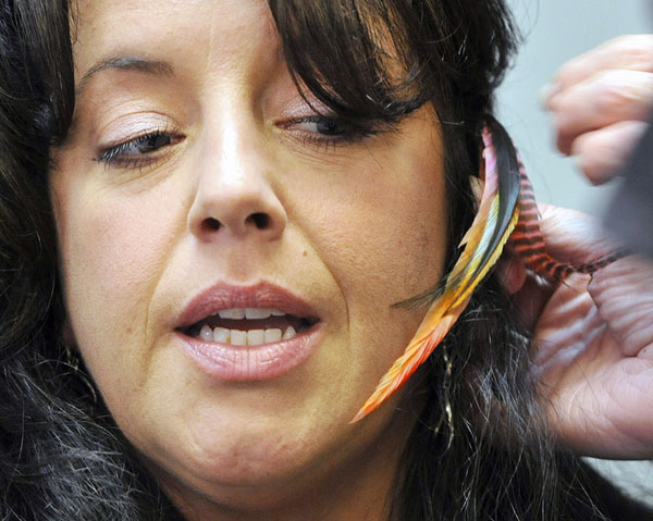 Stylist Tracie Goriss eyes the rooster feather she was having put in her hair Thursday at Studio 114 in Westbrook.