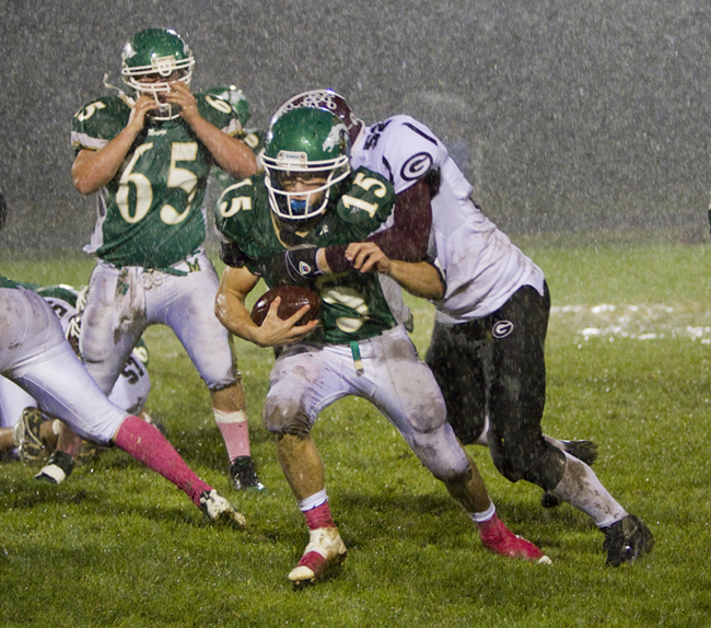 Massabesic quarterback Jake Desrochers attempts to slip past Kyle Nealey of Gorham during their game on a muddy field Friday night. Gorham outscored the Mustangs, 63-47.