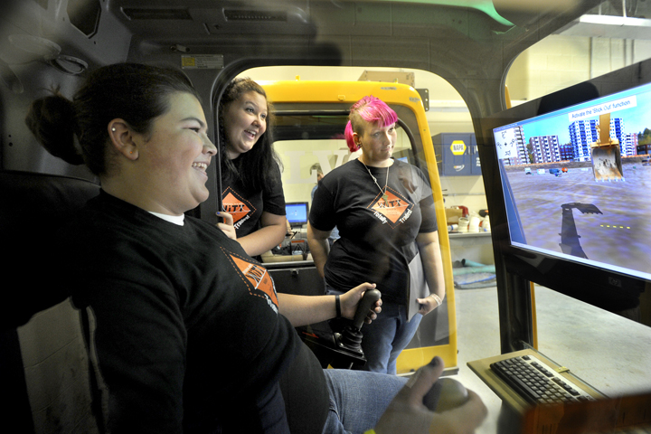 Westbrook students Dominique Segler, Jordan Pitt and Savahna Plummer take turns in the excavator simulator during the conference at Westbrook Regional Vocational Center on Friday.