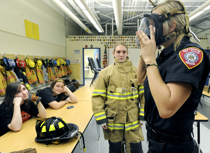 Westbrook High School freshmen Mackenzie Souza and Paige Fogg watch Westbrook firefighter and paramedic Rachael Welch demonstrate gear she wears to a fire as Westbrook Regional Vocational Center hosted the Totally Trades Conference.