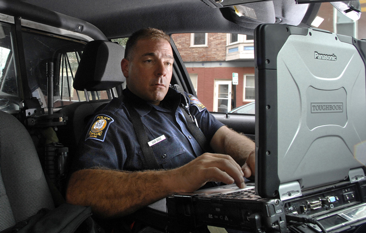 Portland patrolman Danny Rose checks his mobile data terminal while parked on Portland Street on Thursday. Police are not exempt from the new law that makes texting while driving illegal.