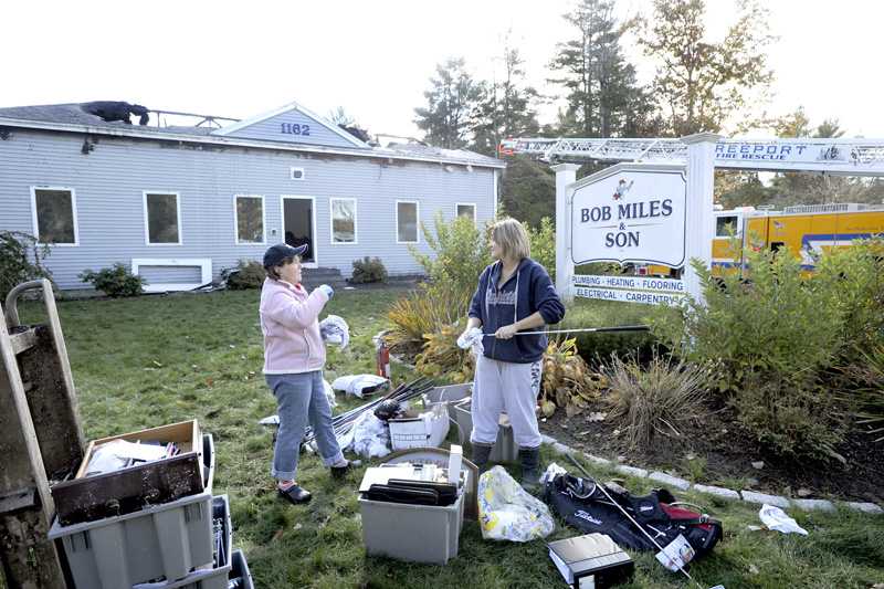 Jane Miles and Samantha Maheux help with the cleanup Tuesday after a major fire Monday gutted Bob Miles & Son’s contracting business in Freeport.