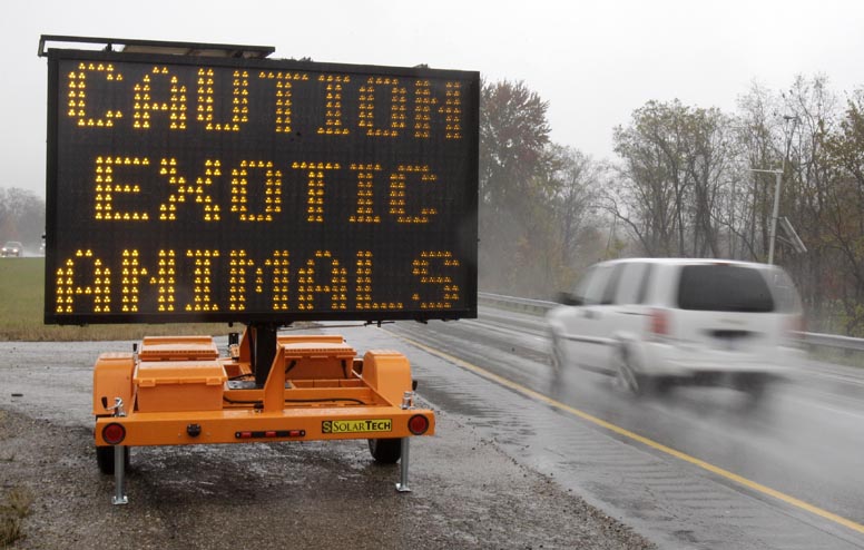 A sign warning motorists that exotic animals are on the loose stands next to I-70 today near Zanesville, Ohio.