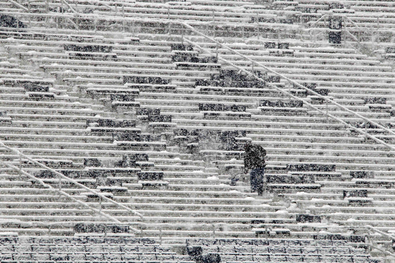 A worker shovels snow from the seats in preparation for an NCAA college football game between Penn State and Illinois at Beaver Stadium in State College, Pa., today.