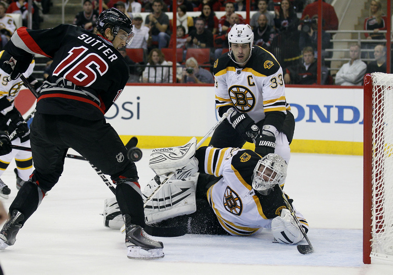 Bruins goalie Tim Thomas falls to the ice to stop Carolina's Brandon Sutter in tonight's game at Raleigh, N.C. The Bruins were beaten, 3-2.